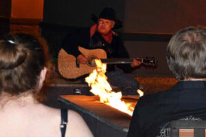 A man playing a guitar by the campfire