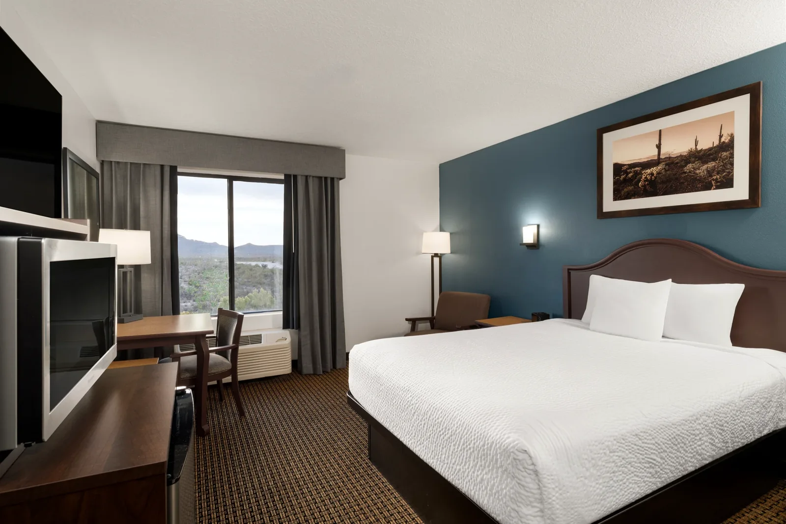King guest room with desk, television and window